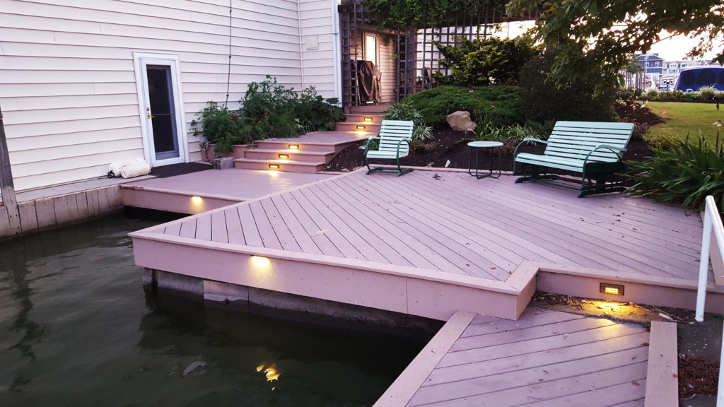 Deck ontop of water with patio and path lighting during dusk