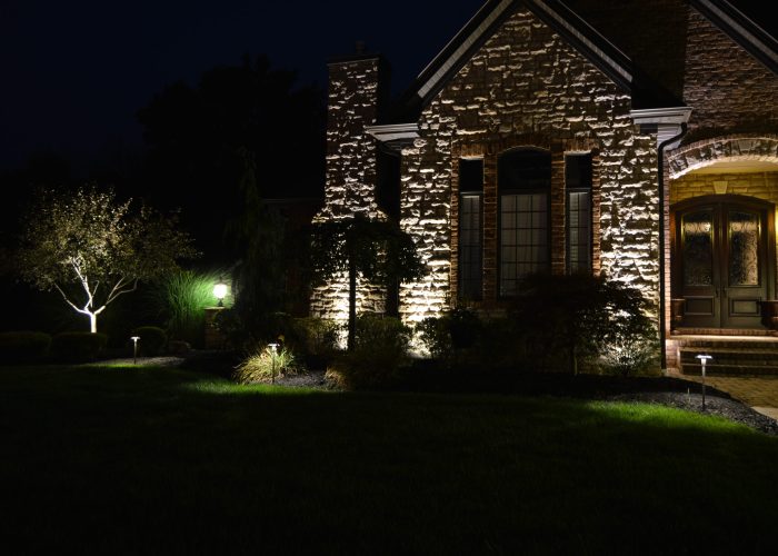 Accent lighitng on brick siding of house showing windows and landscape in front