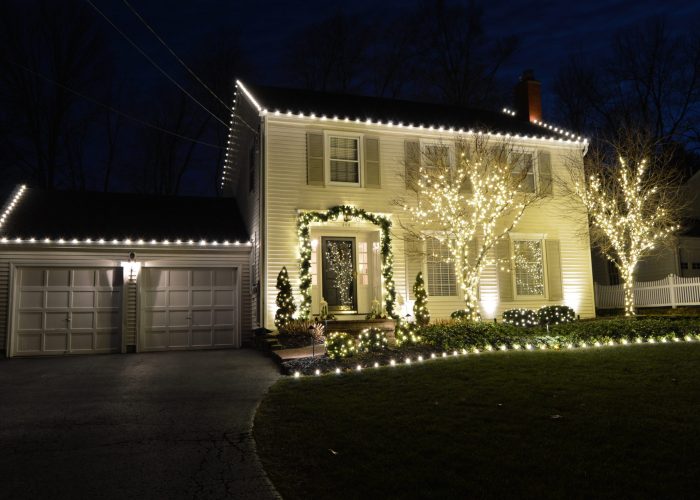 Holiday and spotlighting at a two story two car garage white house
